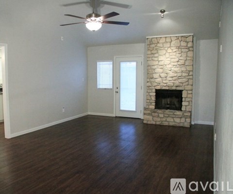 A room with a stone fireplace and a ceiling fan.