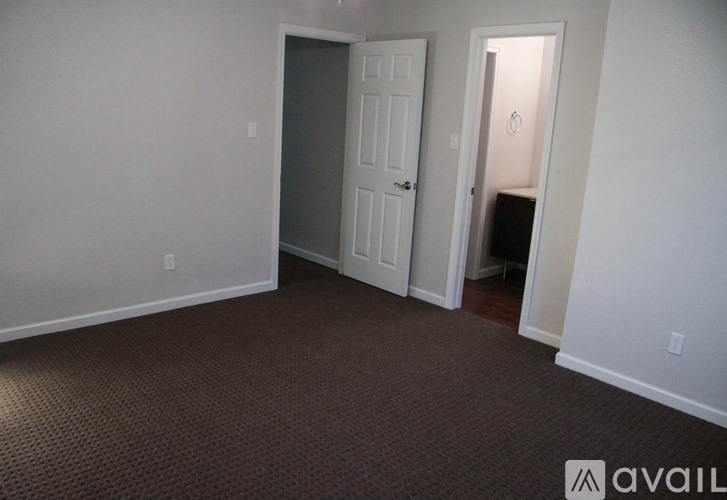A room with a carpeted floor and two doors.