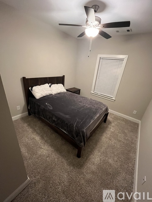 A bedroom with a bed, carpet, and a ceiling fan.