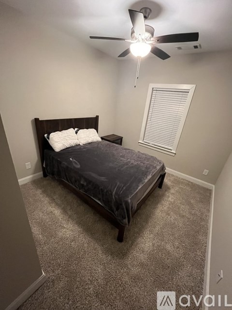 A bedroom with a bed, carpet, and a ceiling fan.