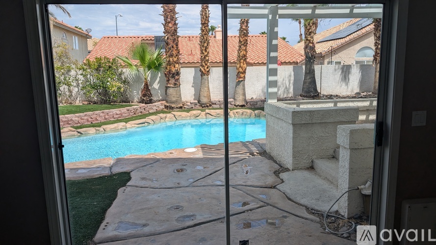 A pool surrounded by a stone patio and palm trees.