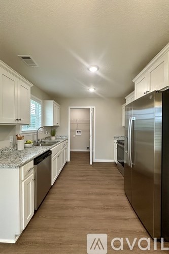 A kitchen with white cabinets and a stainless steel refrigerator.