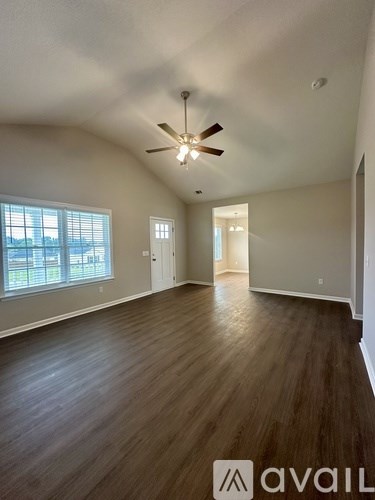 A spacious room with wooden flooring and a ceiling fan.