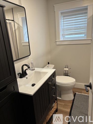 A bathroom with a sink, toilet, and mirror.