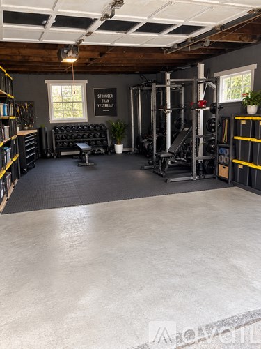 A gym with a grey floor and a black couch.