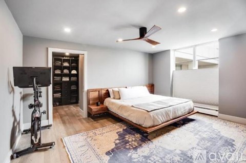 A bedroom with a bed, a fan, and a bicycle.