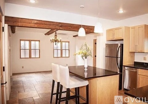 A kitchen with a table and chairs in front of a refrigerator.