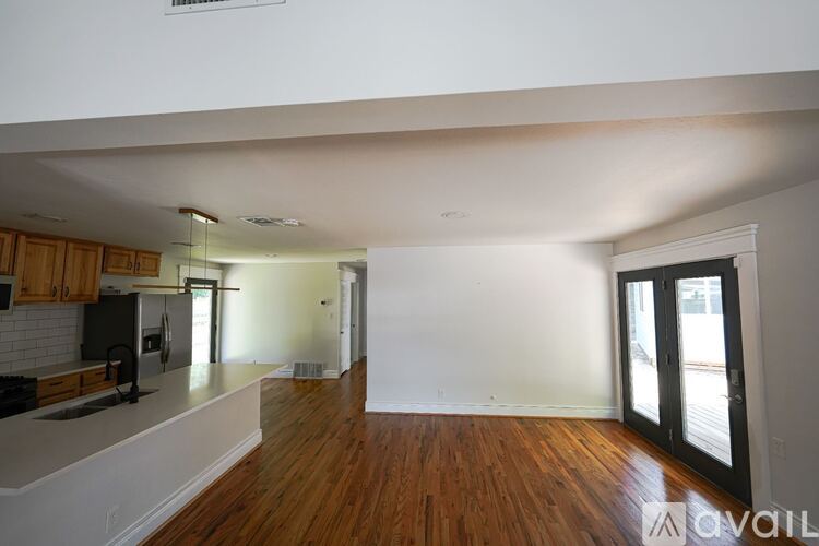 A kitchen with wooden floors and a black fridge.