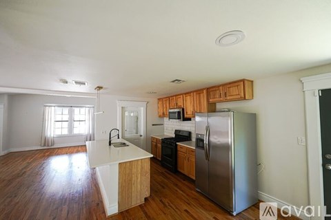 A kitchen with wooden cabinets and a stainless steel refrigerator.