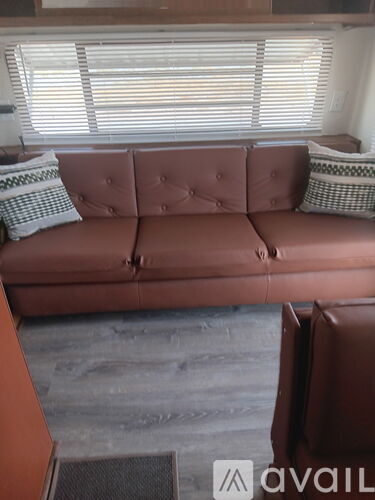 A brown couch with a tufted back and two pillows on it.