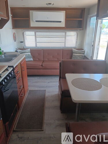 A kitchen with a brown couch and a white table.