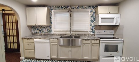 A kitchen with a sink, stove, and microwave.