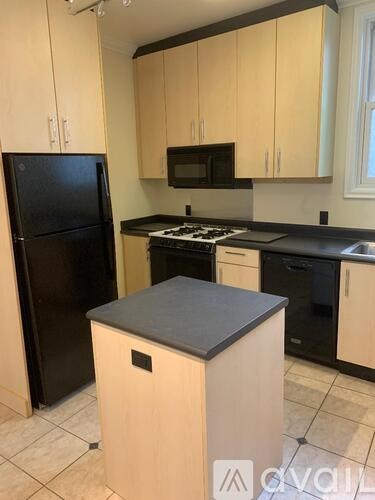 A kitchen with black appliances and wooden cabinets.