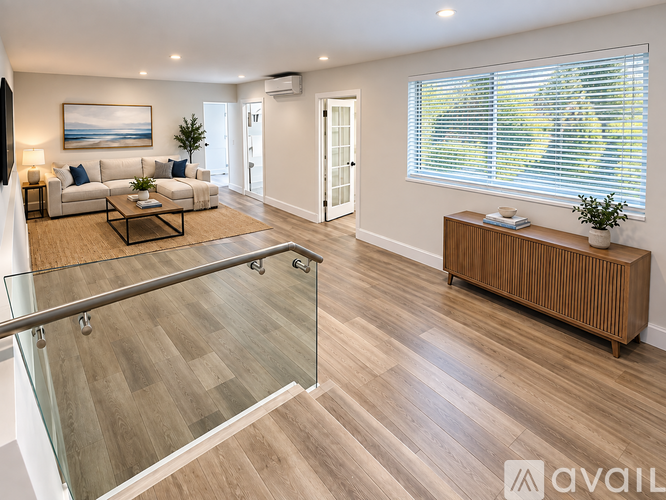 A spacious living room with a glass railing and a wooden floor.