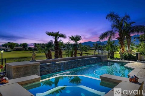 A pool surrounded by palm trees at dusk.