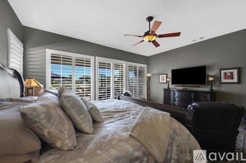 A bedroom with a large bed and a ceiling fan.