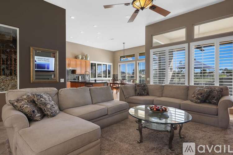 A living room with a large couch, a coffee table, and a flat screen TV.