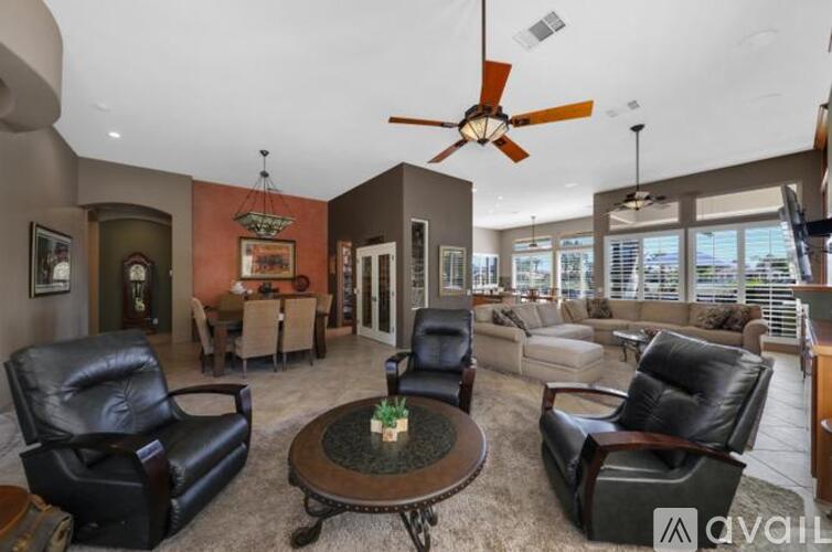 A living room with a fan and leather chairs.