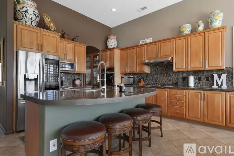 A kitchen with wooden cabinets and a large island with bar stools.