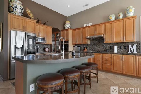 A kitchen with wooden cabinets and a large island with bar stools.