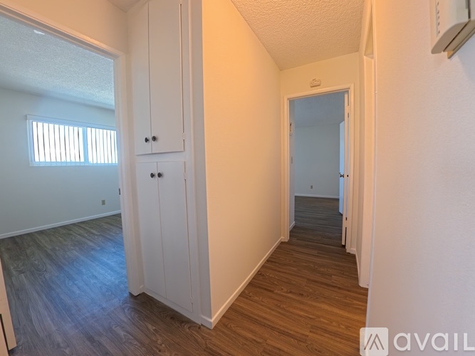 A room with wooden floors and white walls, with a cabinet and a door visible.