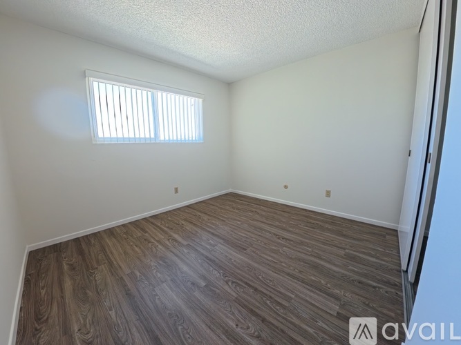 A room with wooden flooring and a window with blinds.