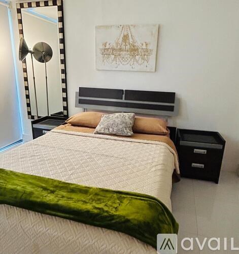 A bedroom with a bed, a bench, a lamp, and a painting on the wall.