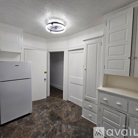 A kitchen with white cabinets and a white fridge.