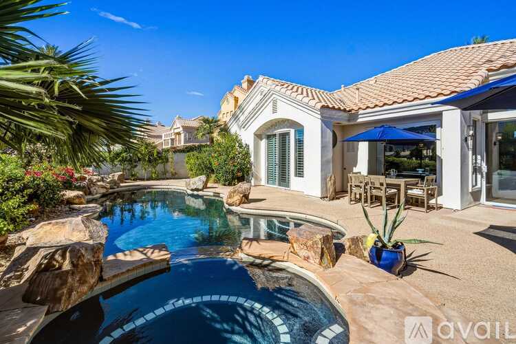 A pool surrounded by a patio and a house.