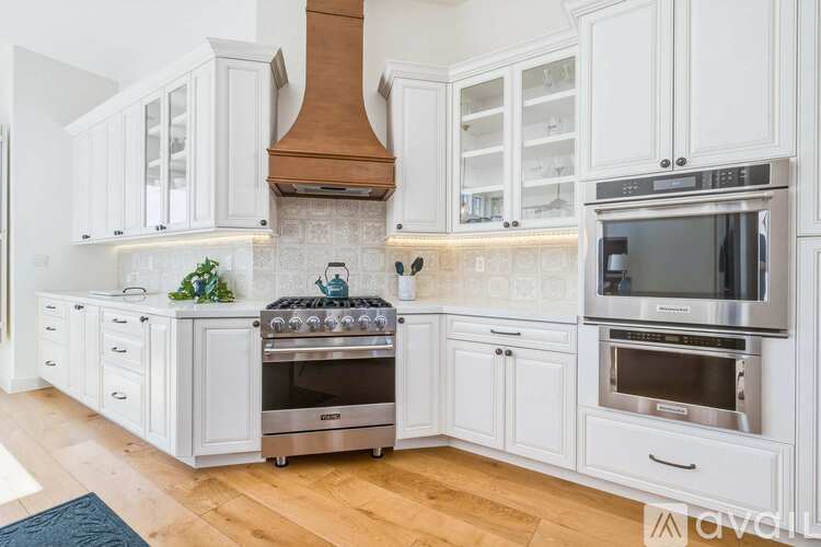 A modern kitchen with white cabinets and stainless steel appliances.