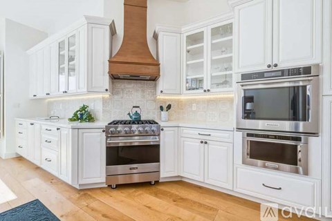 A modern kitchen with white cabinets and stainless steel appliances.