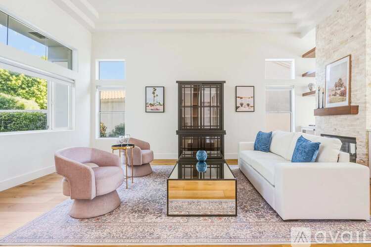 A living room with a white couch, a pink armchair, and a wooden coffee table.