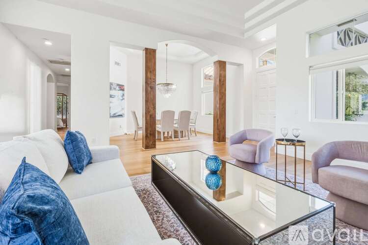A modern living room with a glass coffee table and a white sofa.