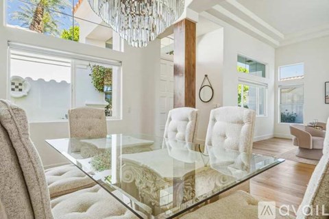 A modern dining room with a glass table and chairs.