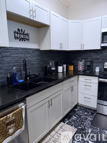 A kitchen with white cabinets and black countertops.