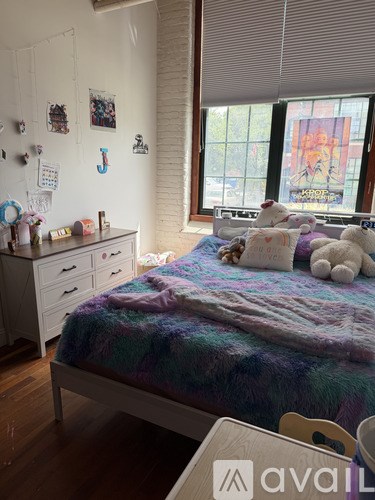 A bedroom with a bed, dresser, and window.