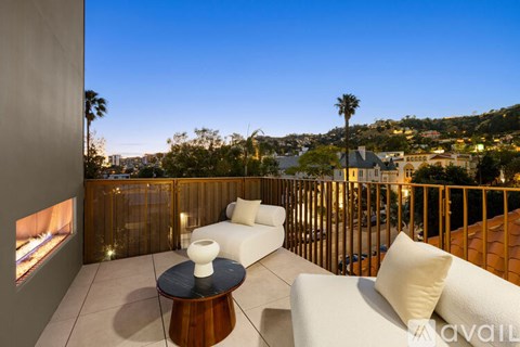 A balcony with a table and chairs overlooking a cityscape at dusk.