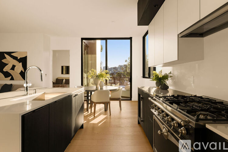 A modern kitchen with a black stove top oven and wooden flooring.