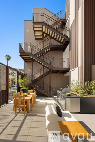 A modern outdoor dining area with a staircase leading to a balcony.