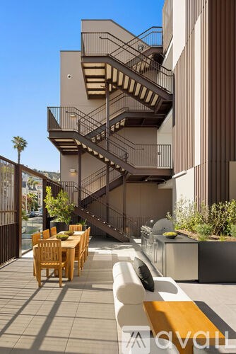 A modern outdoor dining area with a staircase leading to a balcony.