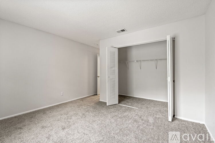 A bedroom with a carpeted floor and a white closet.