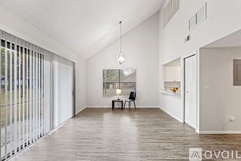 A modern living room with a wooden floor and a large window with blinds.