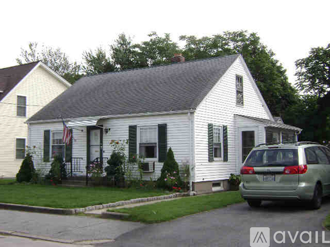 A white house with a grey car parked in front.