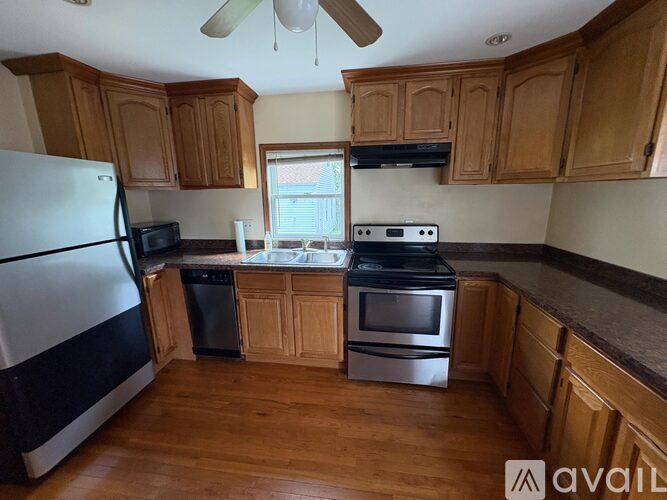 A kitchen with wooden cabinets and a black fridge.