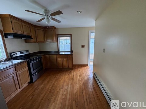 A kitchen with wooden floors and a ceiling fan.
