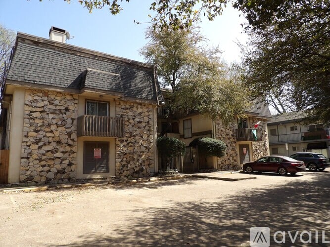A stone building with a balcony is surrounded by trees.