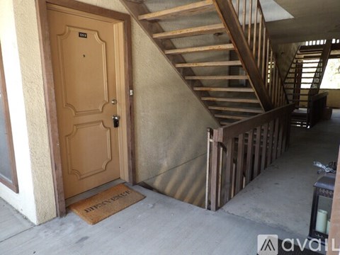 A wooden door with a glass window is on the left and a wooden staircase is on the right.