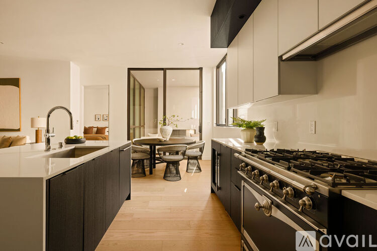 A modern kitchen with a black stove top oven and wooden flooring.