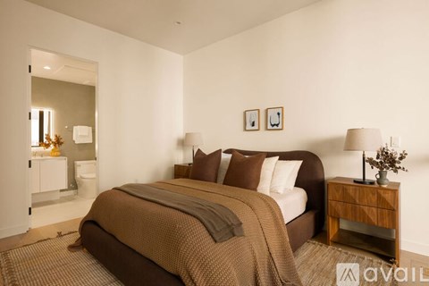A bedroom with a large bed and a wooden nightstand.