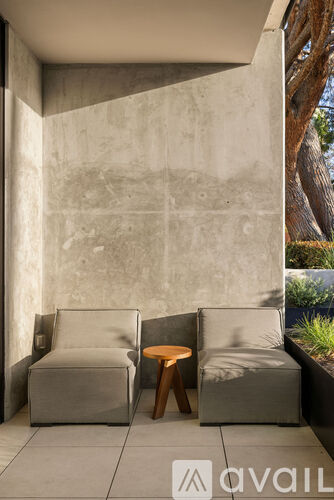 Two grey couches and a small table are in front of a concrete wall.